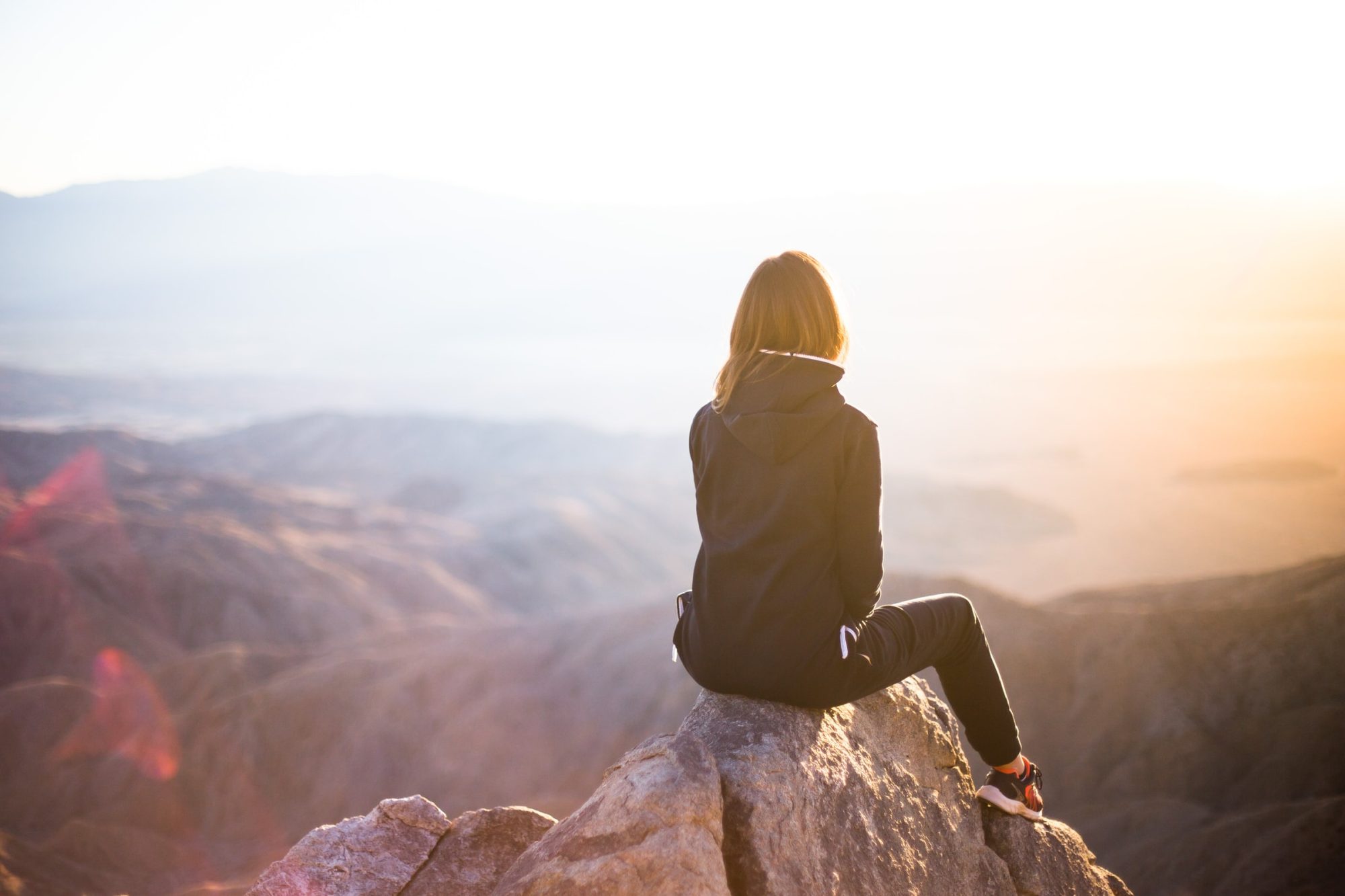 woman looking at sunset sitting on a mountain